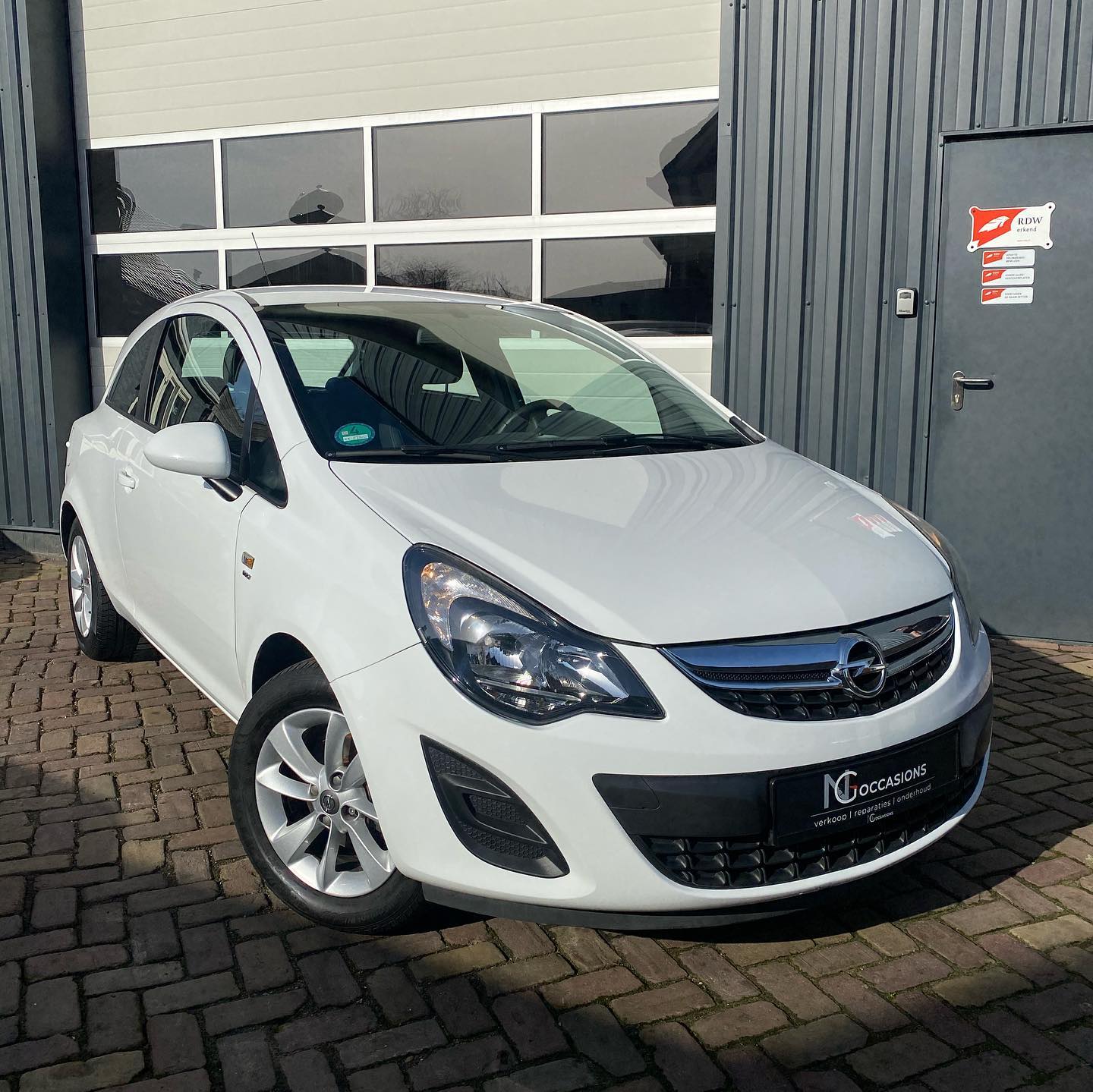 Een auto voor de werkplaats van NG Occasions, met het RDW bord naast de deur